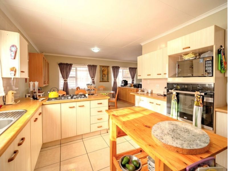 A functional kitchen featuring light-toned cabinetry, laminate countertops, a gas hob, and a built-in oven, with tiled flooring and an open-plan layout.