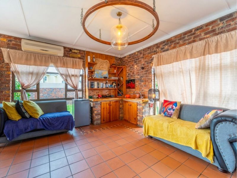 A cozy living area featuring exposed brick walls, tiled flooring, and built-in wooden cabinetry with integrated storage.