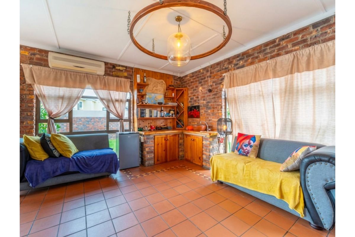 A cozy living area featuring exposed brick walls, tiled flooring, and built-in wooden cabinetry with integrated storage.
