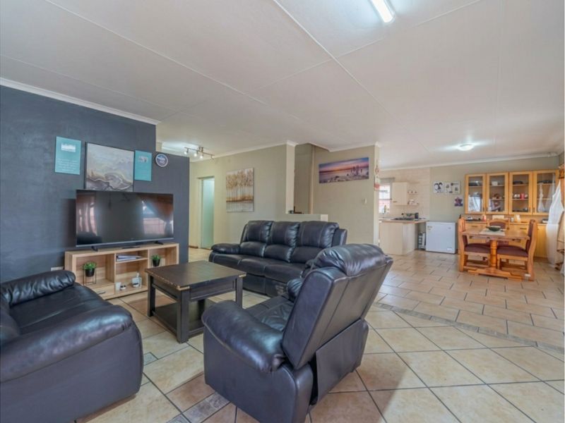 Spacious open-plan living and dining area featuring ceramic tile flooring and an integrated kitchen space with built-in cabinetry.