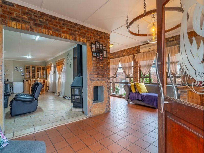 Open-plan living area featuring exposed brick walls, tiled flooring, and a central freestanding fireplace, creating a warm and rustic atmosphere.