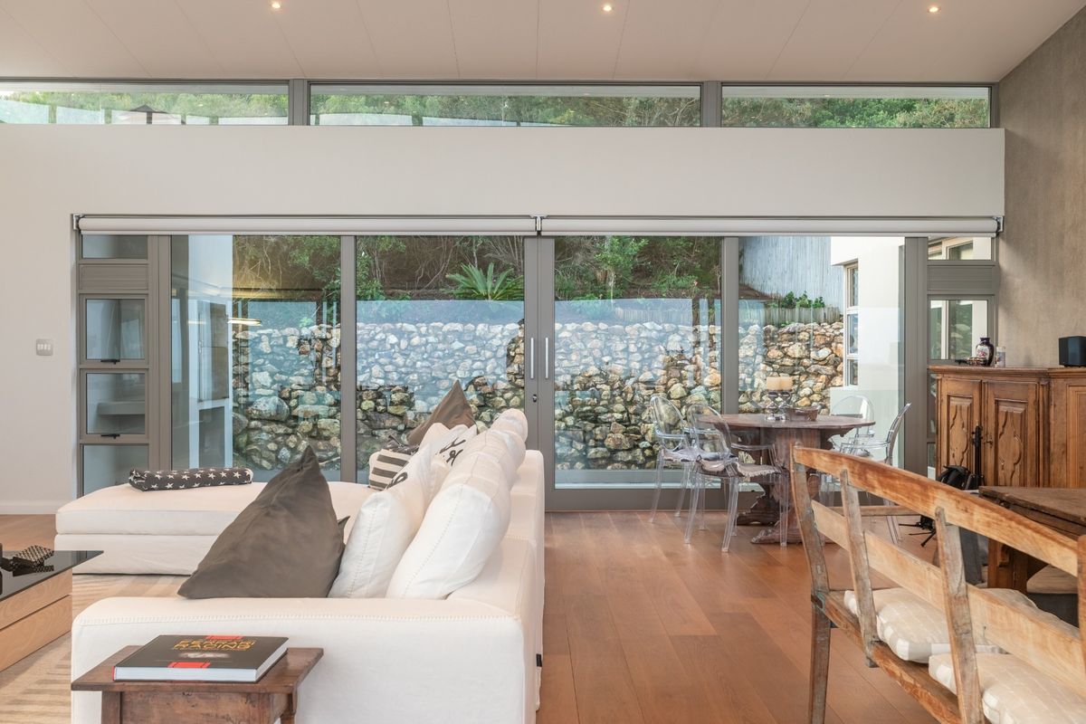 Spacious living area featuring hardwood flooring, recessed lighting, and expansive sliding glass doors that open to a private stone-walled garden terrace.