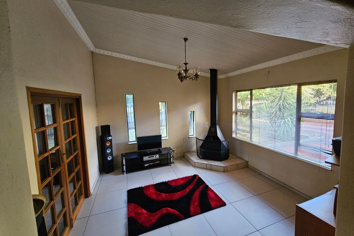 Spacious living room featuring a vaulted ceiling, tiled flooring, and a prominent freestanding fireplace, offering a bright and functional living space.