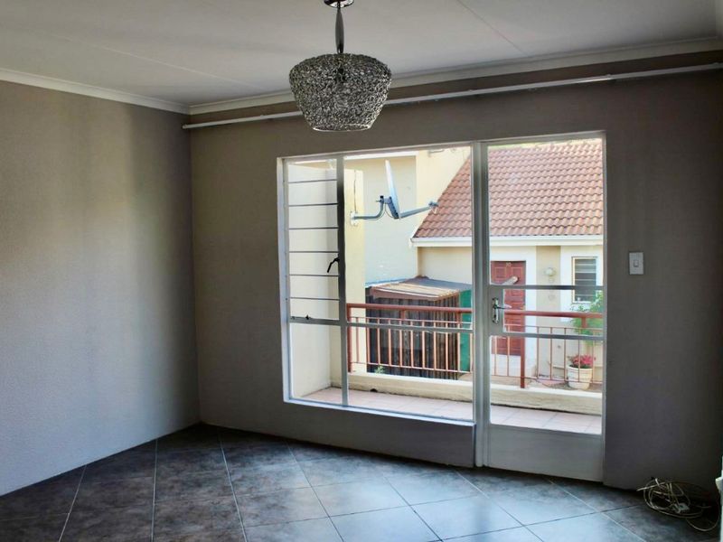 An empty living area featuring tiled flooring and a large glass door providing access to a private balcony.