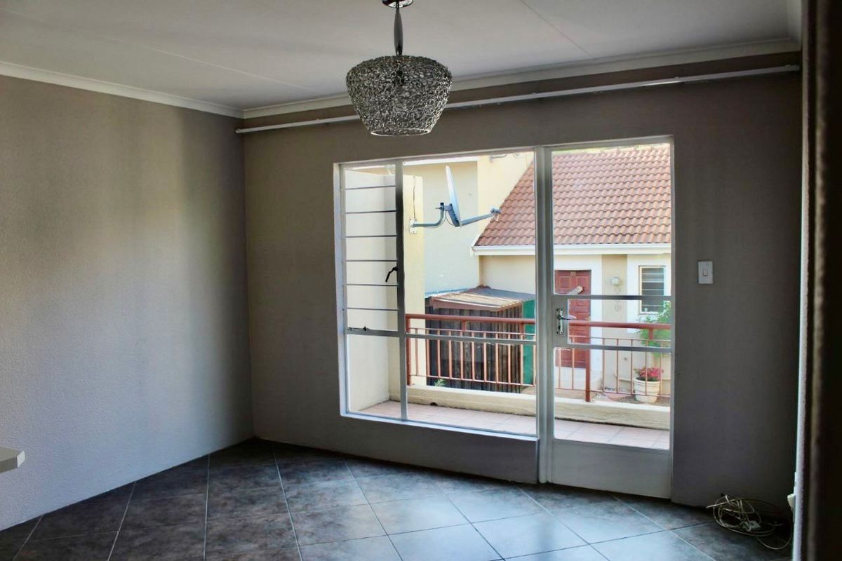 An empty living area featuring tiled flooring and a large glass door providing access to a private balcony.