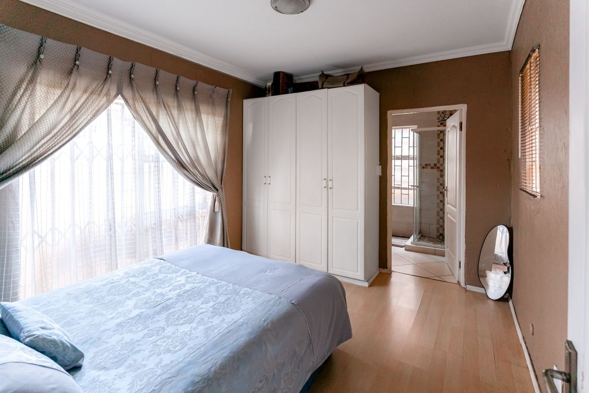 A bedroom featuring built-in wardrobes, laminate flooring, and an en-suite bathroom access.