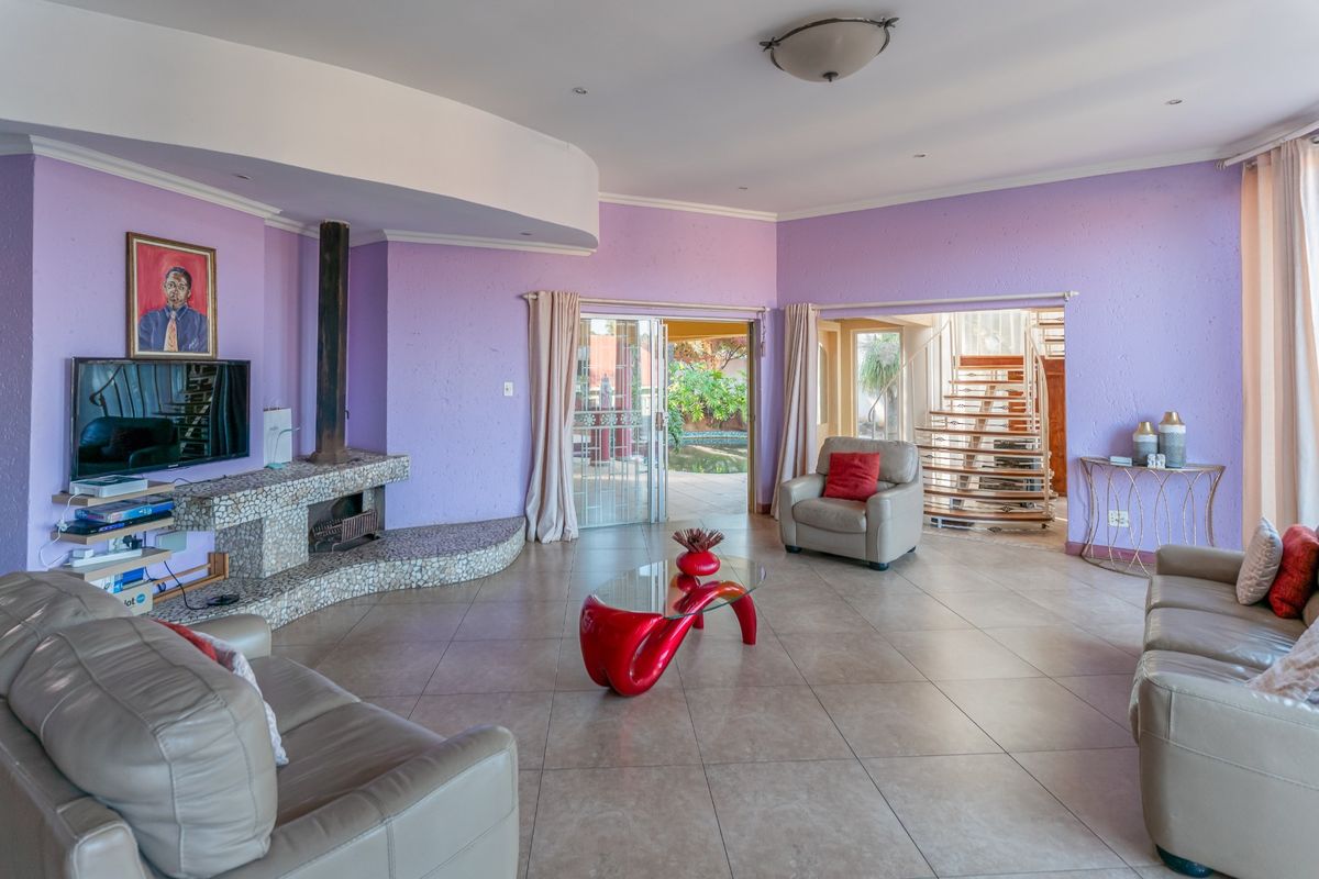 Spacious living room featuring a unique mosaic-tiled fireplace, tiled flooring, and a spiral staircase leading to an upper level.