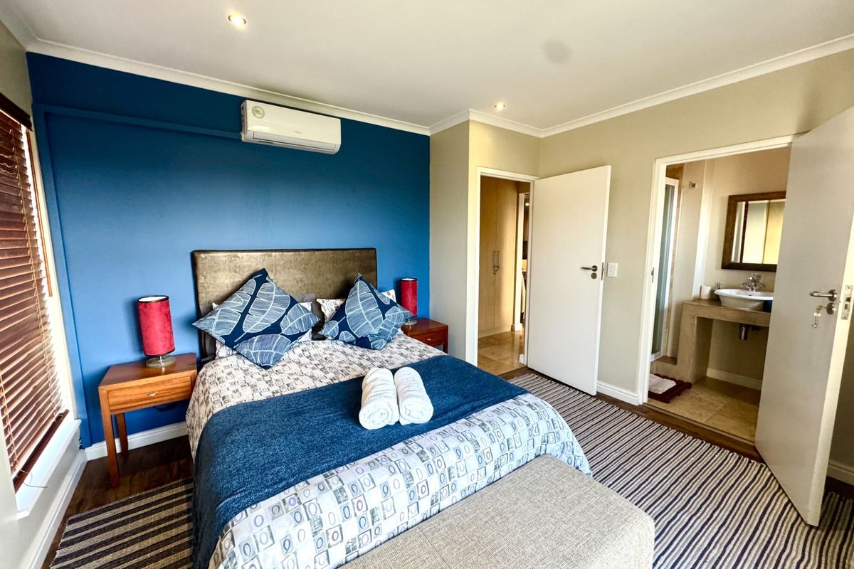 A well-maintained bedroom featuring an en-suite bathroom, split-system air conditioning, and neutral flooring, offering a comfortable and functional living space.