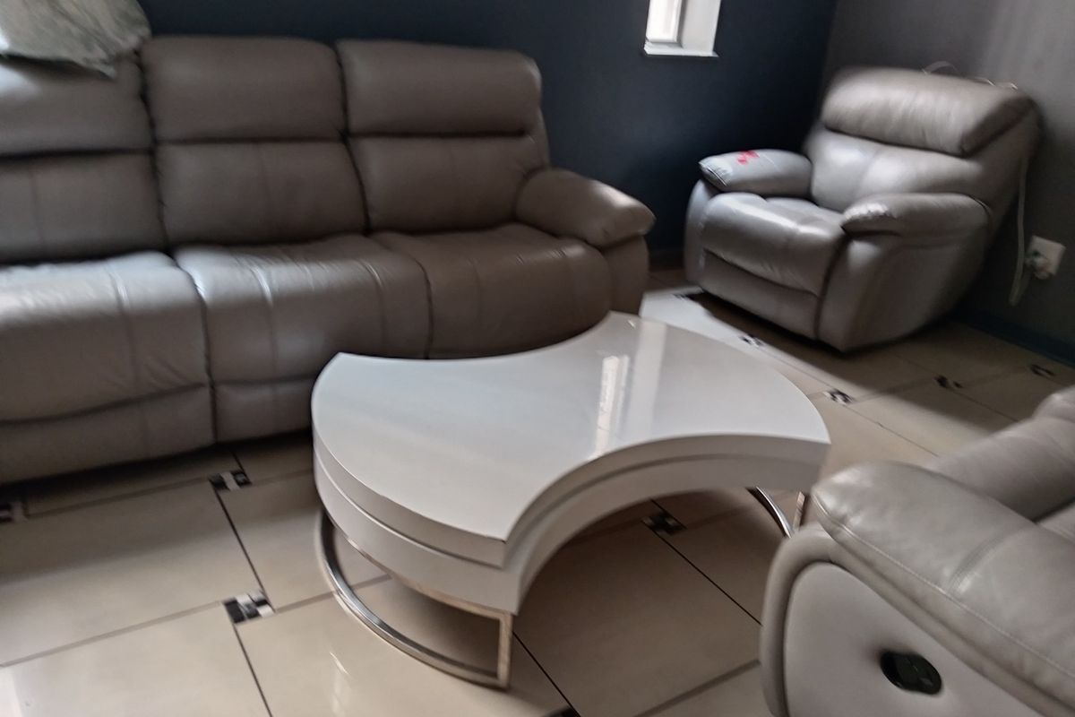 A living room area featuring tiled flooring with decorative inserts and a dark accent wall.