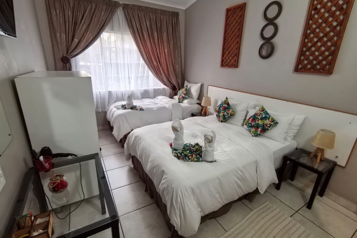 A bedroom featuring tiled flooring, a built-in headboard, and large windows with curtain tracks.