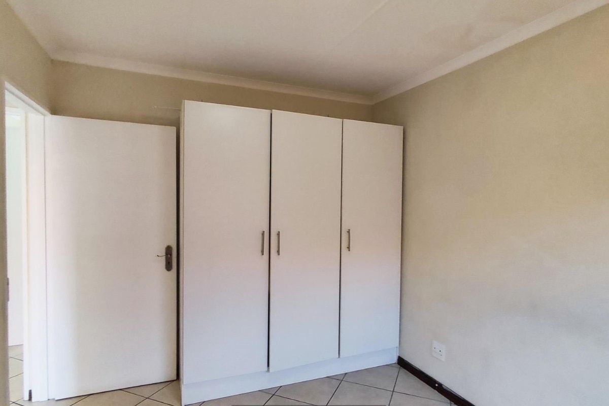 A bedroom featuring built-in white cabinetry, tiled flooring, and a standard interior door.