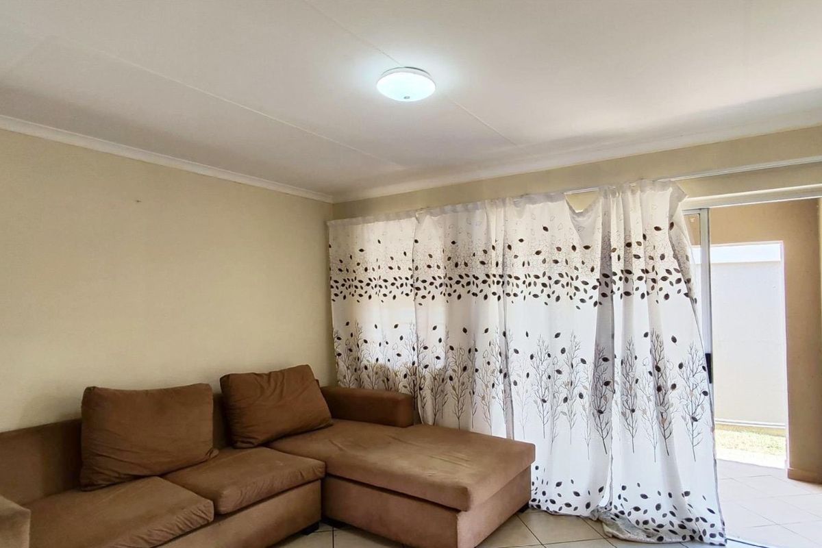 A living room featuring tiled flooring and a sliding glass door providing access to an outdoor patio area.