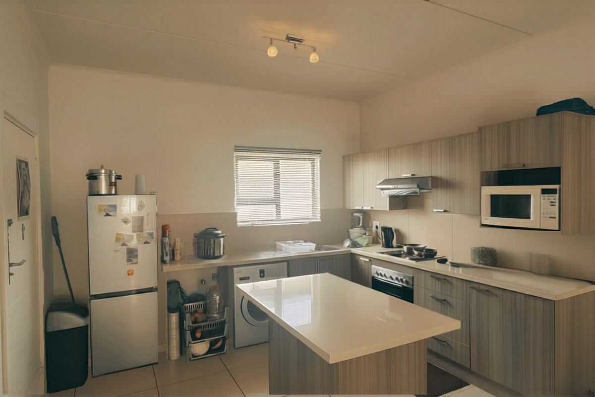 A functional kitchen featuring wood-grain cabinetry, stone-look countertops, a built-in oven, extractor fan, and a central island with integrated storage.