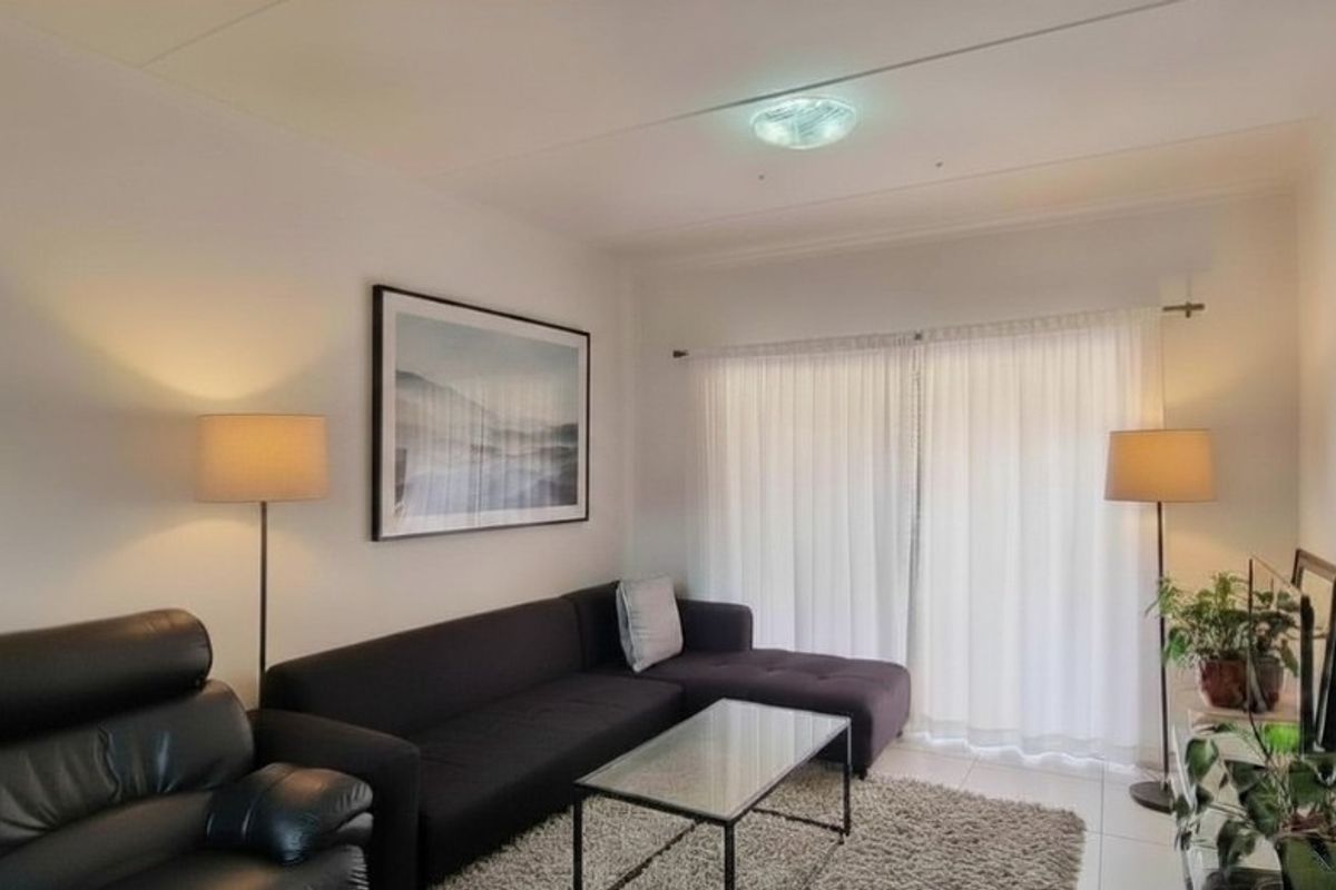 A bright living room featuring tiled flooring and large sliding glass doors that provide access to the outdoor area.