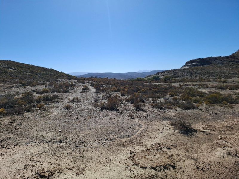 A wide-angle view of the expansive, arid landscape and surrounding hills on this farm property.