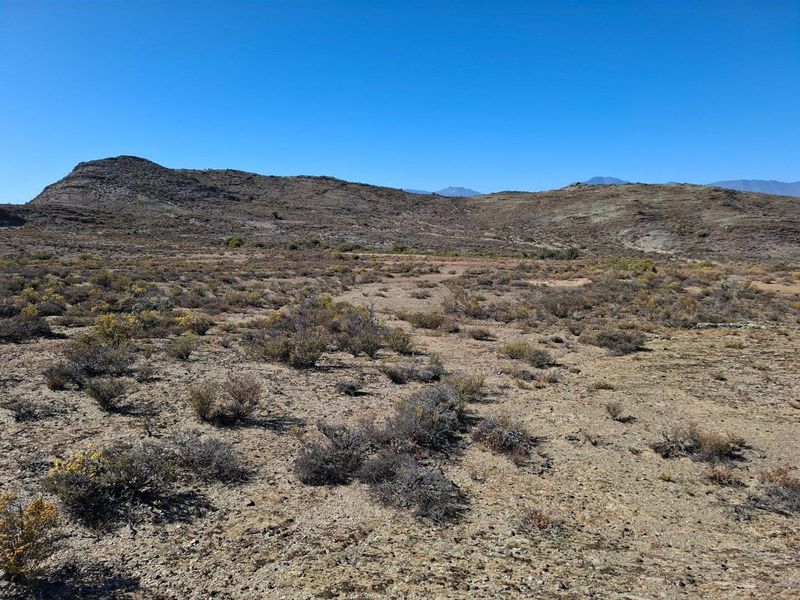 Expansive view of the arid, natural landscape and surrounding hills on the farm property.