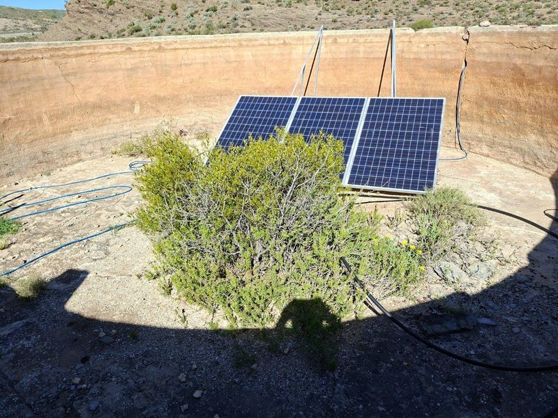 A utility area featuring solar panels installed within a weathered concrete reservoir structure, showing signs of wear and vegetation growth.