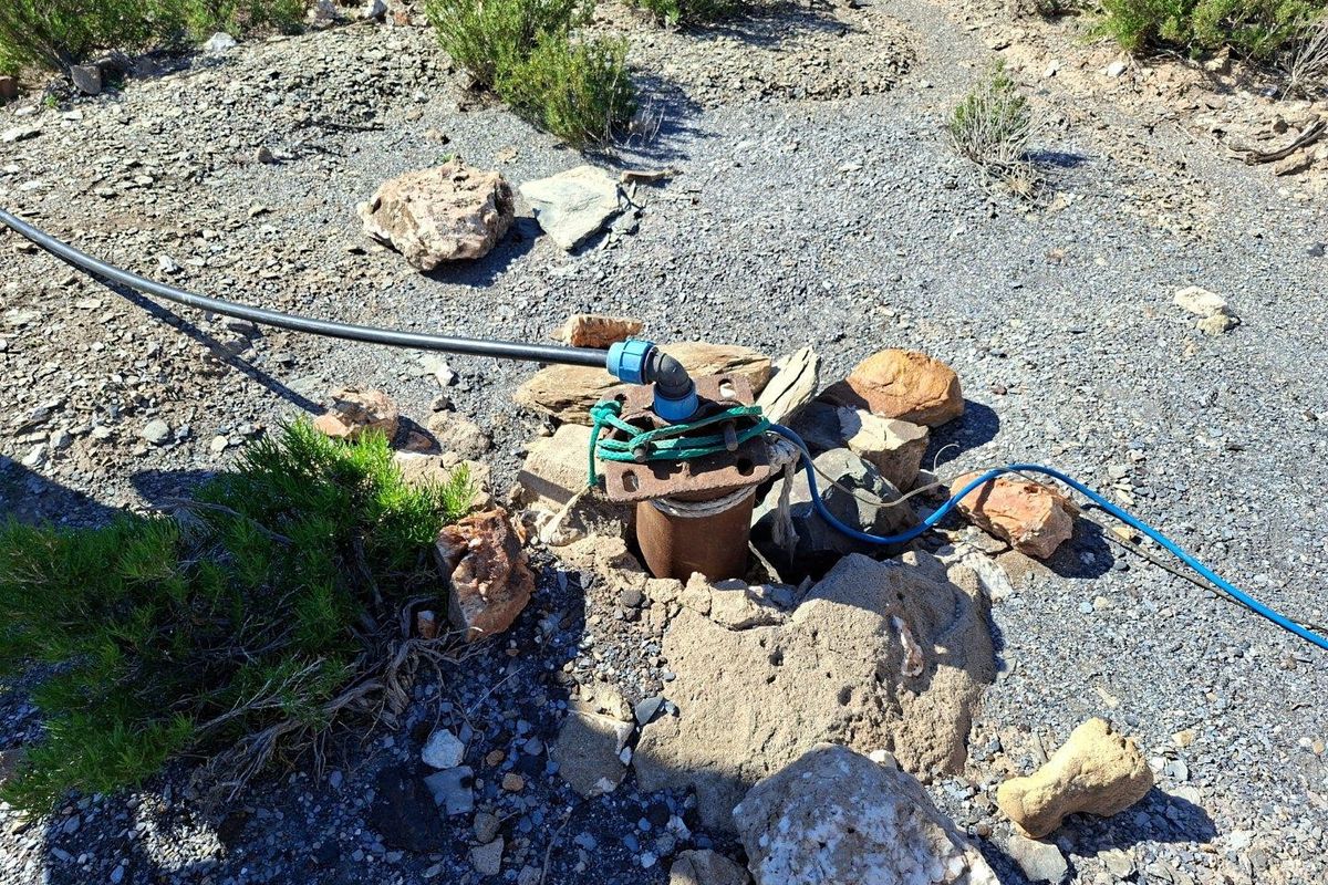 An exposed borehole installation on the property, featuring basic piping and electrical connections requiring maintenance and proper protective housing.