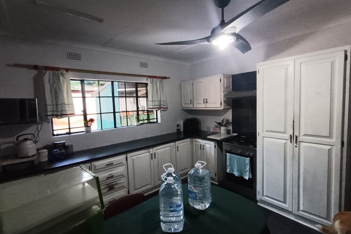 A functional kitchen featuring white cabinetry, dark countertops, a built-in oven with extractor fan, and a ceiling fan.