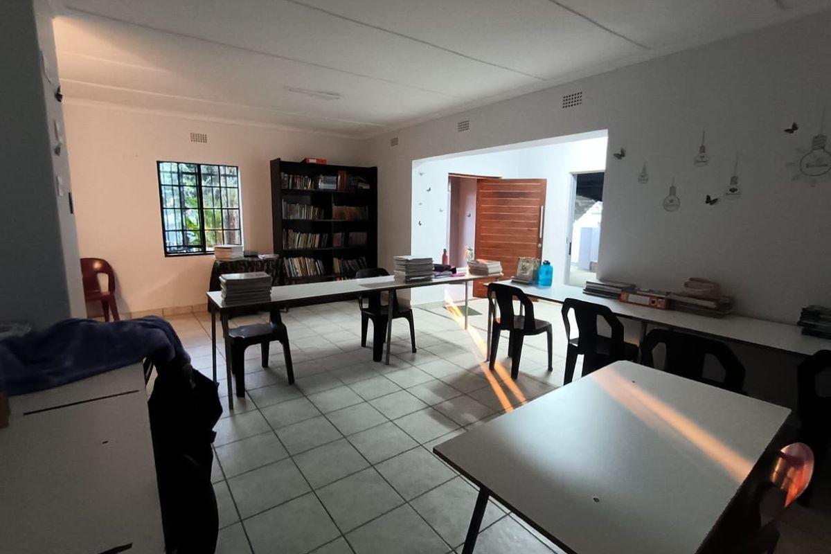 A functional multi-purpose room featuring tiled flooring, large windows, and direct access to an exterior entrance.