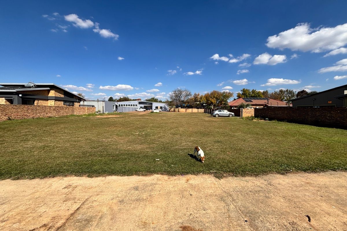 A large, open vacant plot of land featuring perimeter brick boundary walls and a concrete entrance area, suitable for commercial development.