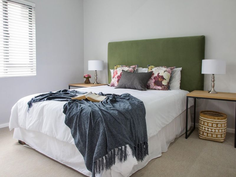 A well-maintained bedroom featuring neutral carpeted flooring and venetian blinds, providing a clean and comfortable living space.