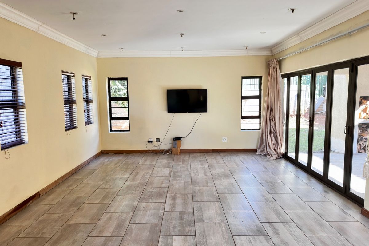 Spacious living room featuring wood-look ceramic floor tiles, recessed ceiling lighting, and large folding glass doors providing direct access to the outdoor area.