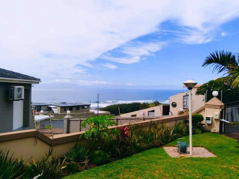 A well-maintained garden area featuring a perimeter wall, outdoor lighting, and a scenic coastal view overlooking the ocean.