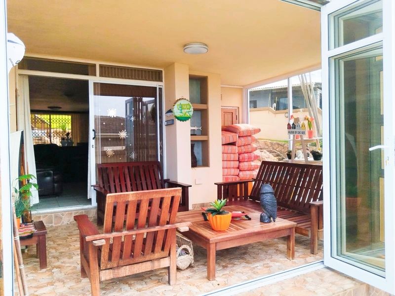 A covered patio area featuring tiled flooring, built-in shelving, and sliding glass doors providing access to the interior living space.
