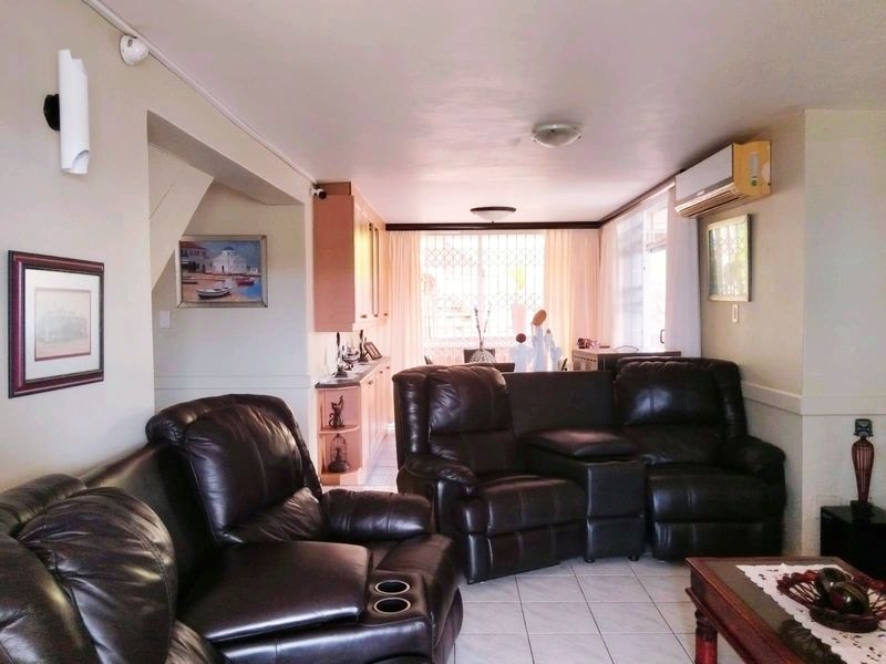 Open plan living area featuring tiled flooring, wall-mounted air conditioning unit, and built-in cabinetry, providing a functional and connected space.