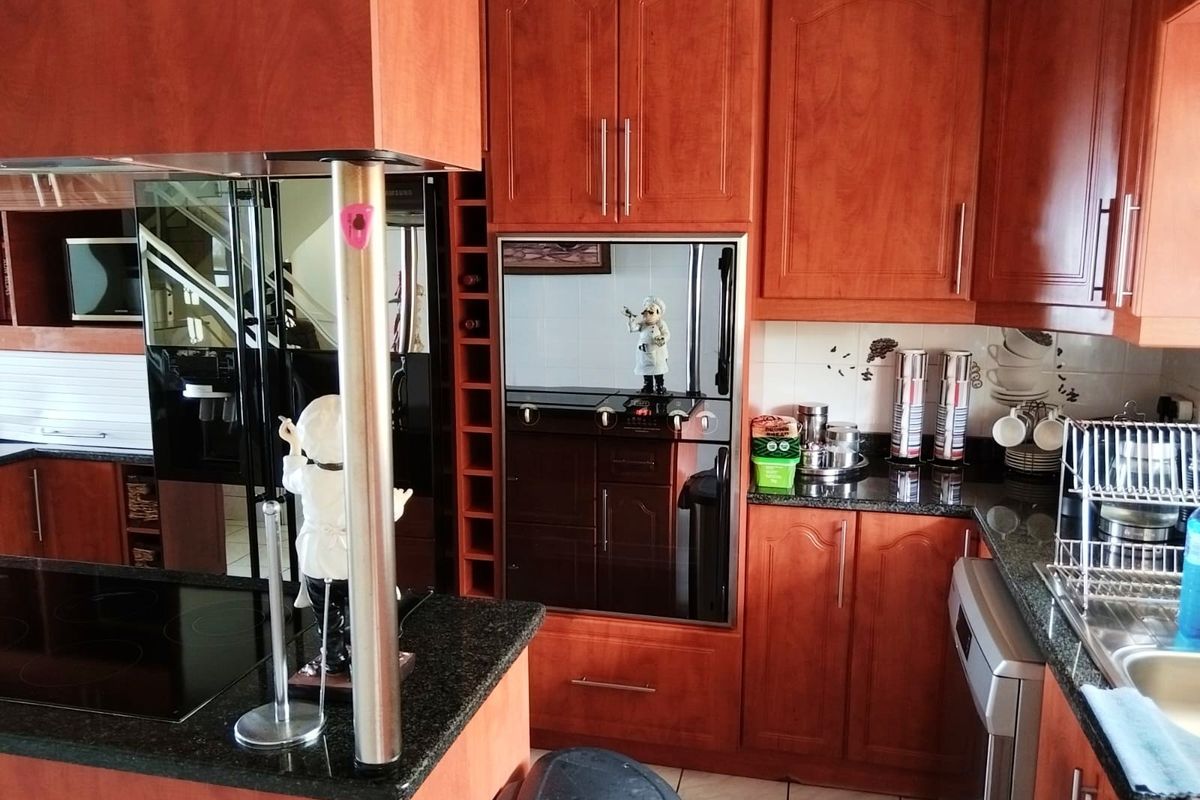 A functional kitchen featuring cherry wood cabinetry, granite countertops, a built-in oven, and a glass-top hob with an integrated extractor fan.