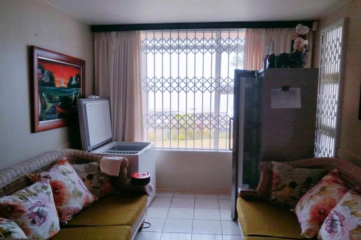 A functional living area featuring tiled flooring and large windows secured with metal security gates, offering natural light and exterior views.