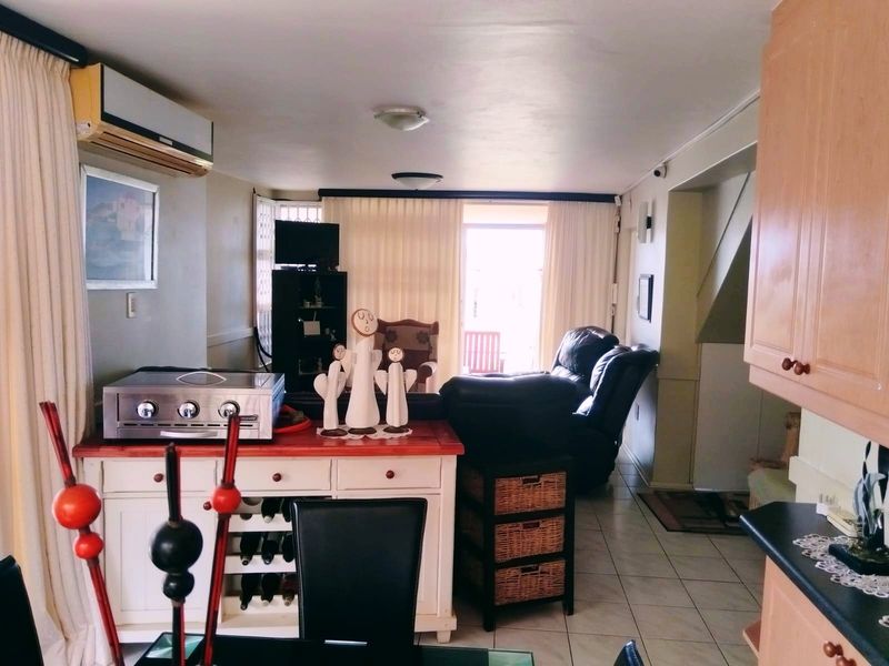 Open plan living area featuring tiled flooring, split-system air conditioning, and direct access to an outdoor patio space.