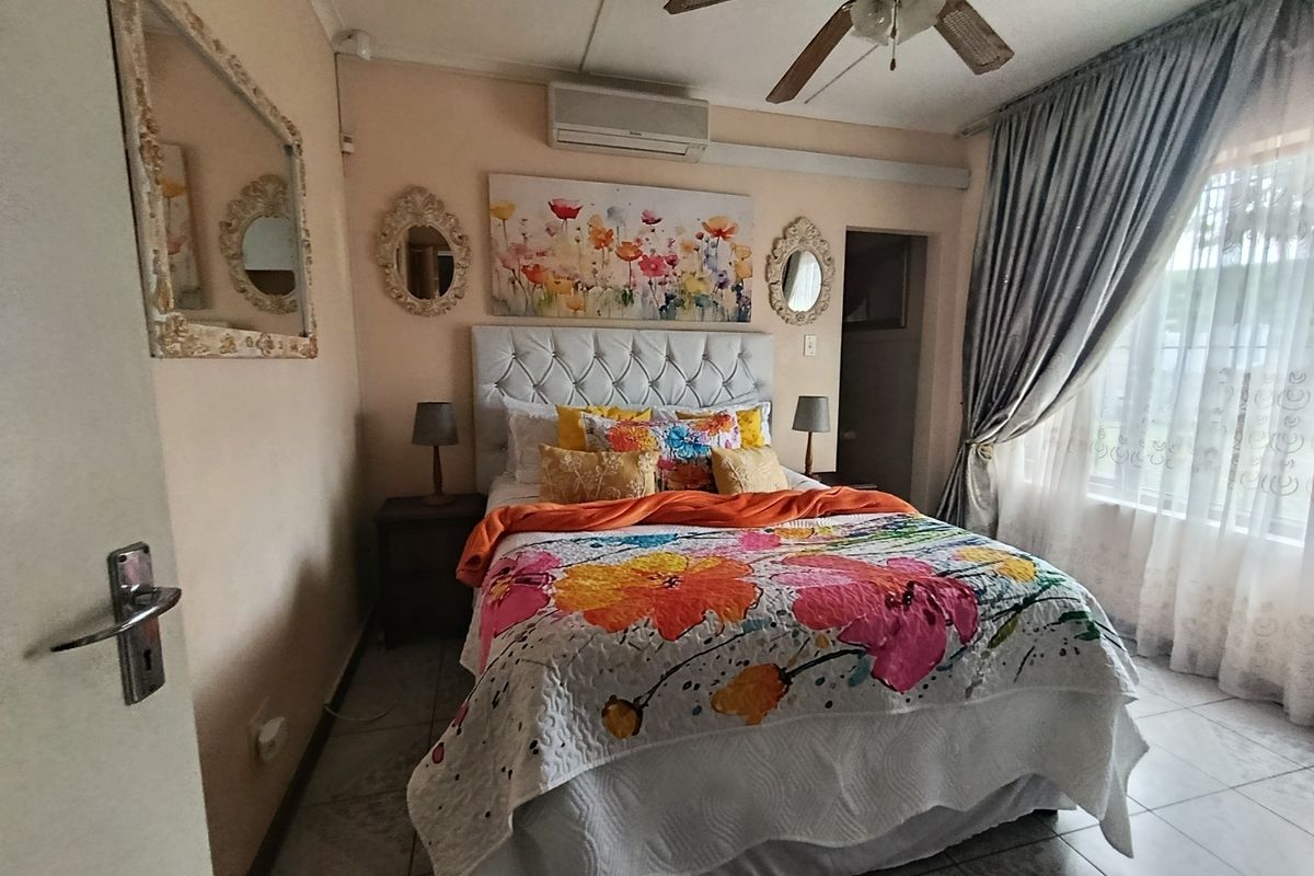 A bedroom featuring tiled flooring, a ceiling fan, and a wall-mounted split-system air conditioner.