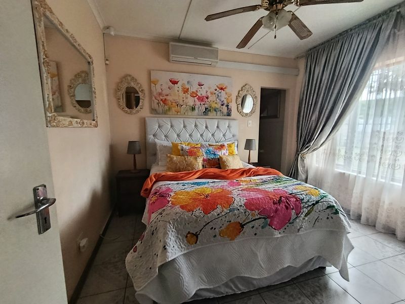 A bedroom featuring tiled flooring, a ceiling fan, and a wall-mounted split-system air conditioner.