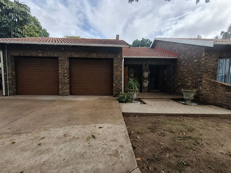 Front elevation of a face brick house featuring a double garage with roll-up doors and a paved entrance area.