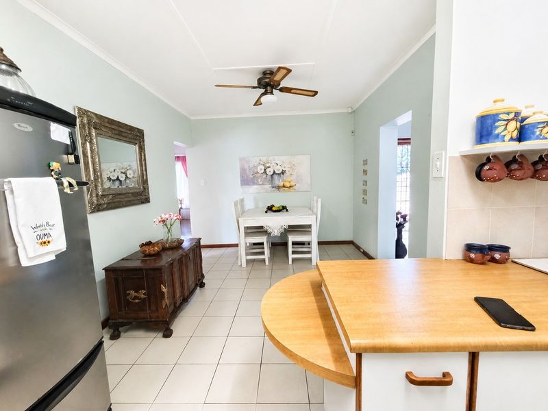 Open plan kitchen and dining area featuring tiled flooring, ceiling fan, and functional cabinetry with laminate countertops.