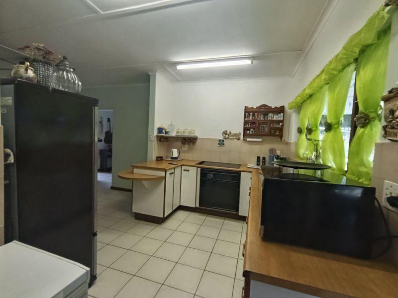A functional kitchen featuring built-in cabinetry, tiled flooring, and integrated cooking appliances, offering a practical layout with potential for modern updates.