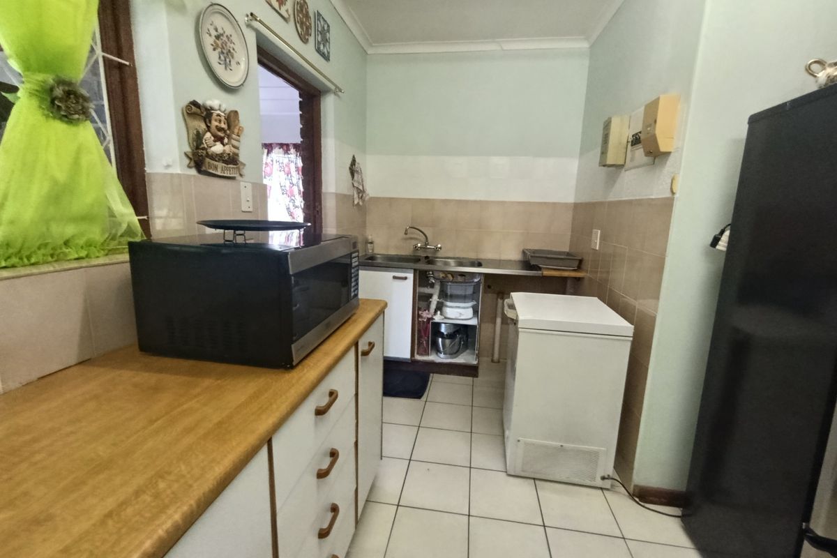 A functional kitchen space featuring tiled flooring, a stainless steel sink, and built-in cabinetry, currently requiring minor repairs to the under-sink area.