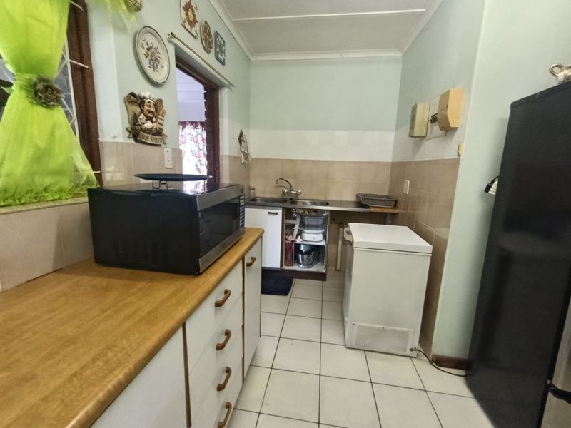 A functional kitchen space featuring tiled flooring, a stainless steel sink, and built-in cabinetry, currently requiring minor repairs to the under-sink area.