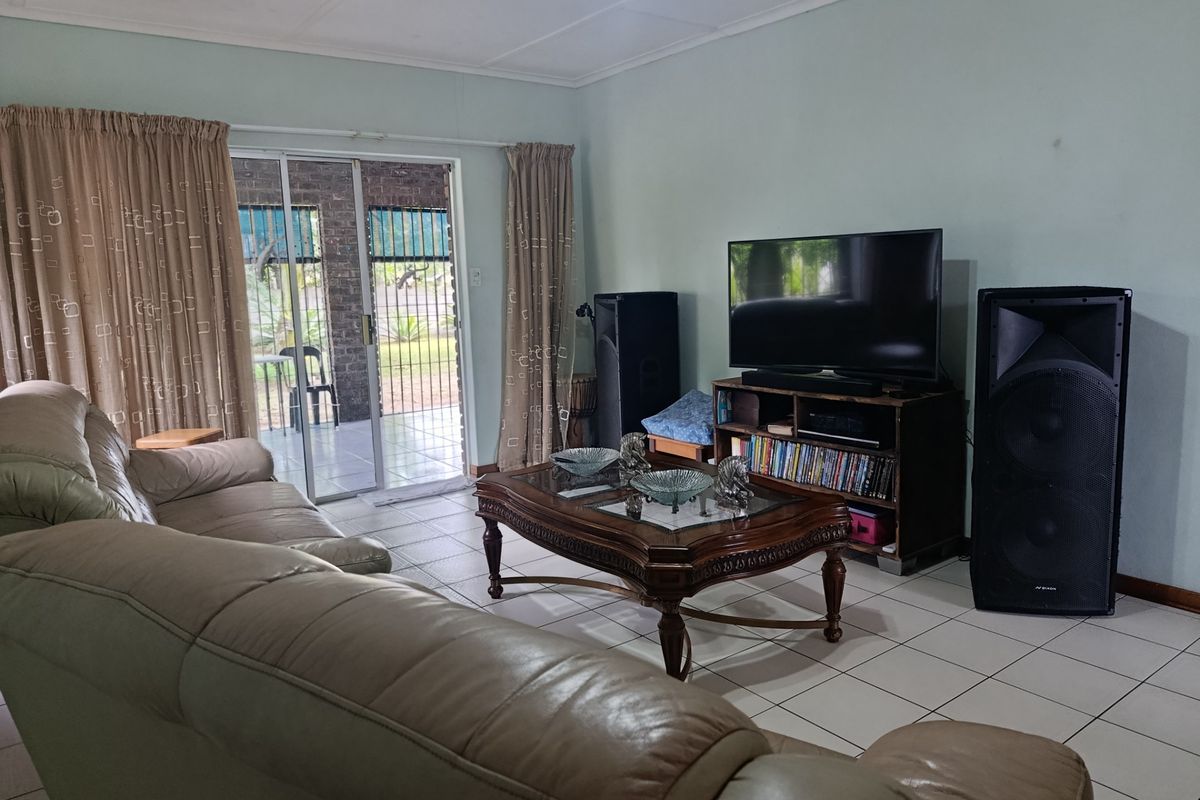 A living room featuring tiled flooring and a sliding glass door providing access to an outdoor patio area.