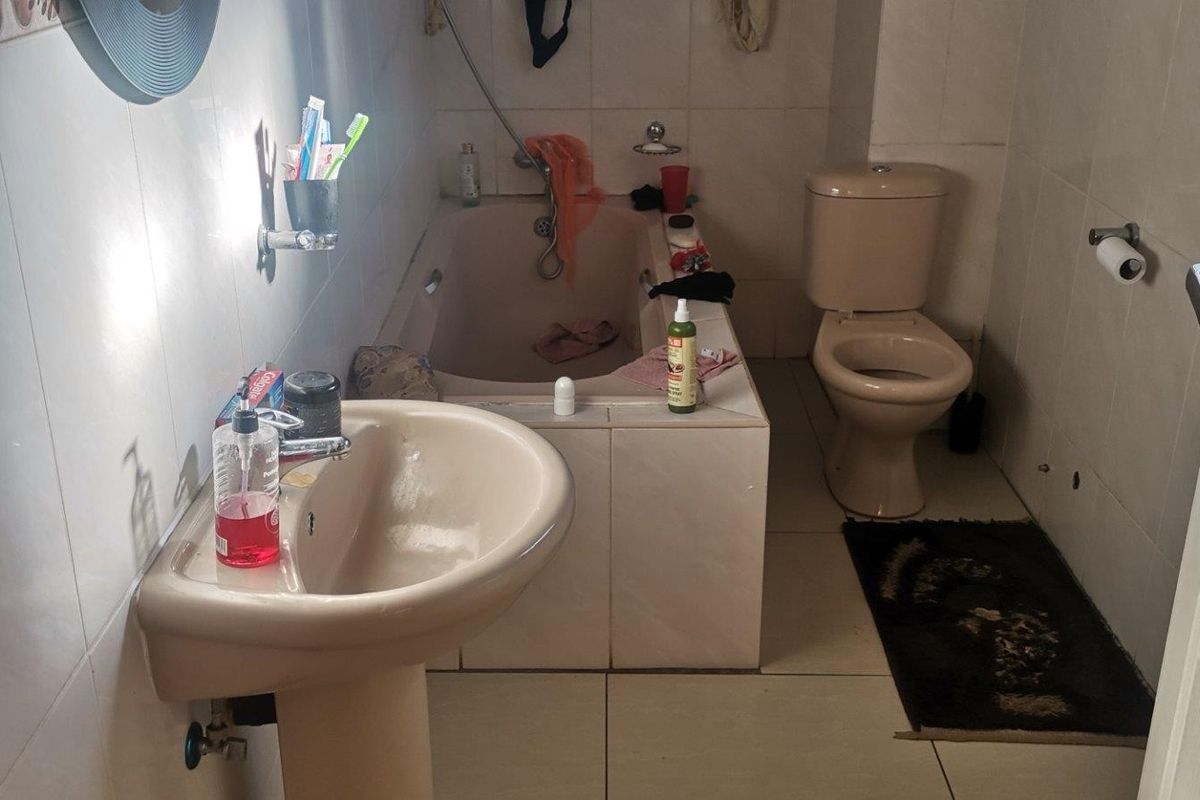 A dated bathroom featuring a pedestal basin, a built-in bathtub, and a standard toilet with tiled walls and flooring.