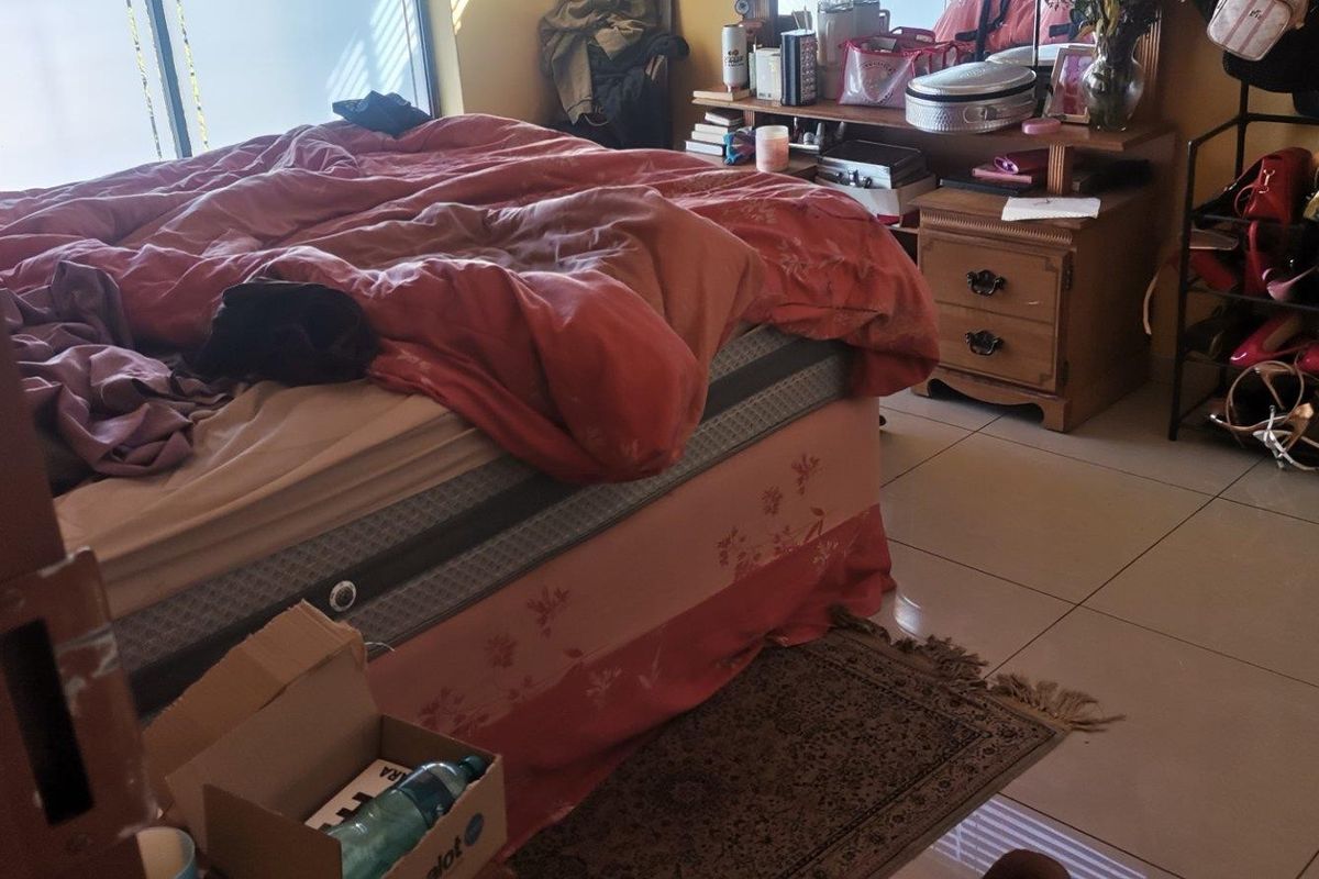 A bedroom featuring tiled flooring and a large window, providing a functional space for rest.