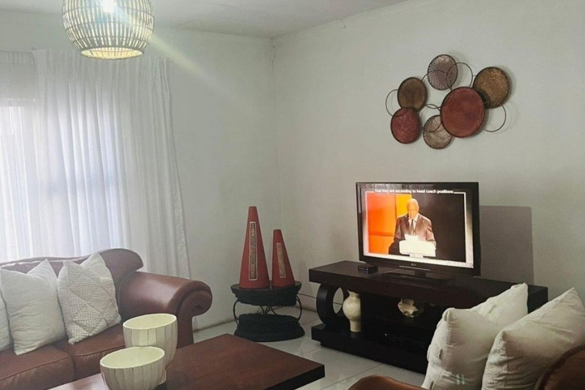 A comfortable living room featuring tiled flooring, neutral walls, and a modern pendant light fixture, creating a functional and inviting space.