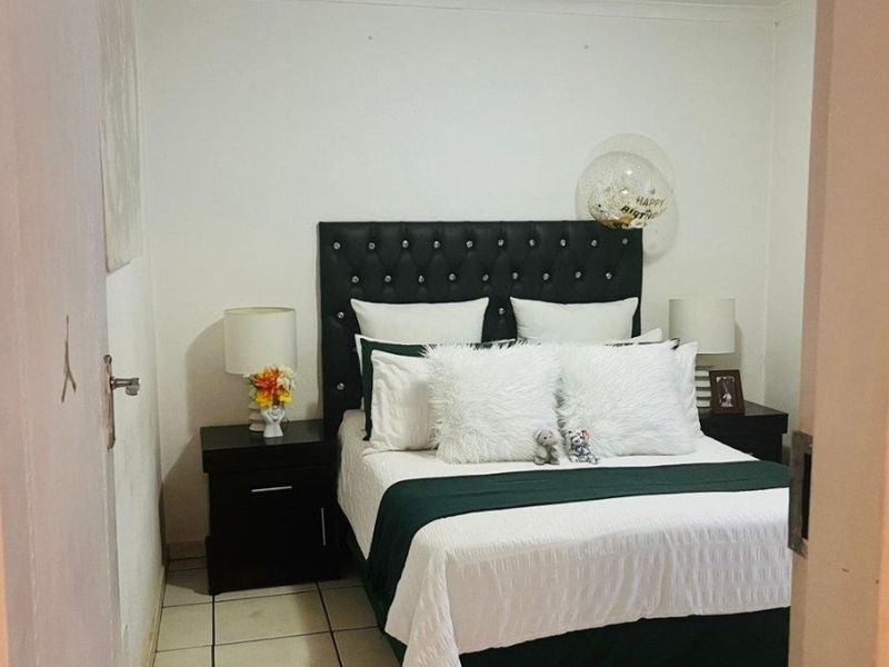 A compact bedroom featuring tiled flooring and a central ceiling light fixture, viewed from the doorway.