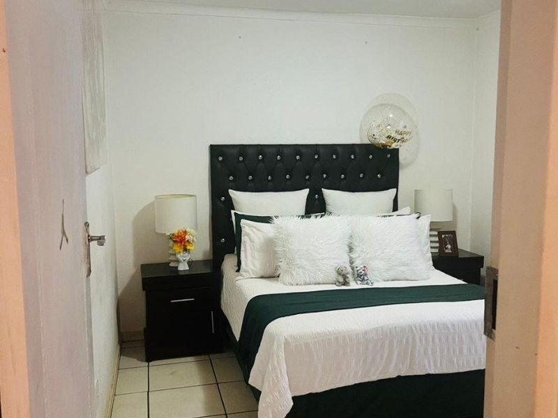 A compact bedroom featuring tiled flooring and a neutral color palette, viewed from the doorway.