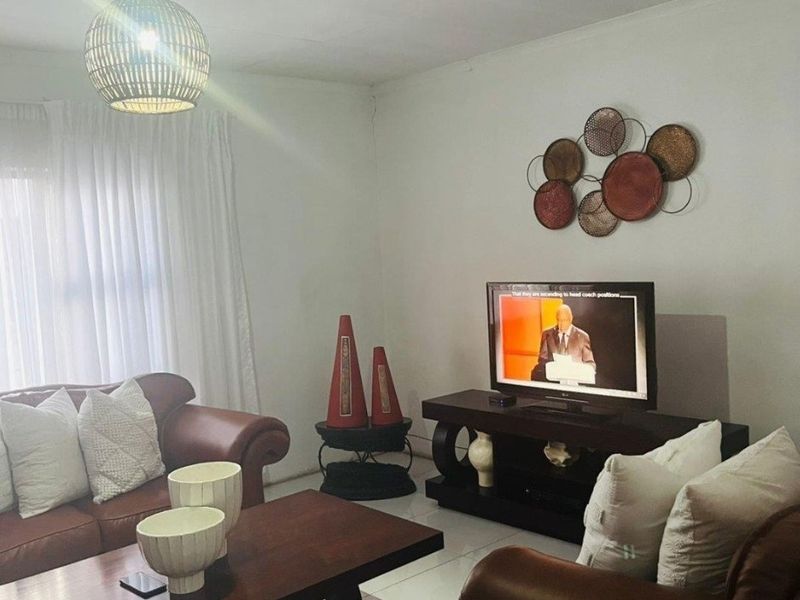 A comfortable living room featuring tiled flooring, neutral walls, and a modern pendant light fixture, creating a functional and inviting space.