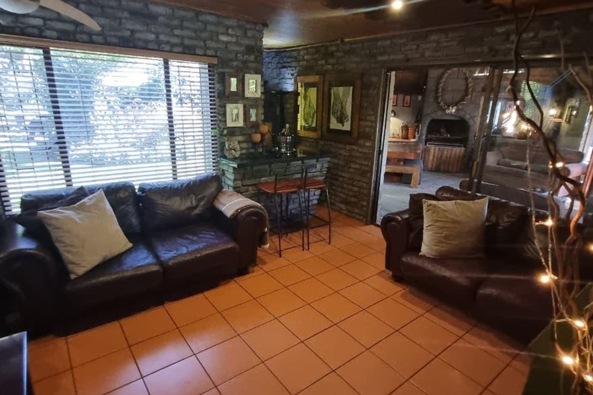 A living room featuring exposed brick walls, terracotta floor tiles, and a built-in bar area, with sliding doors leading to an adjacent space.