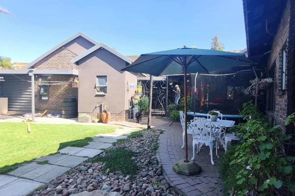 A rear garden area featuring a paved patio, lawn, and brick exterior walls, providing a functional outdoor space for relaxation and entertainment.
