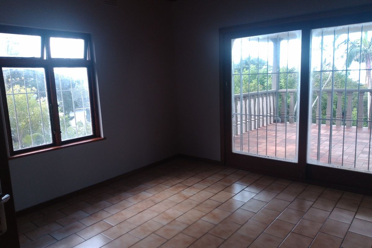 An empty living room featuring tiled flooring and large sliding glass doors that provide direct access to an outdoor balcony area.